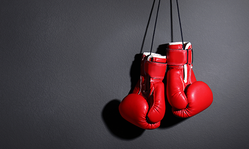 Red boxing gloves hanging on a gark grey background wall
